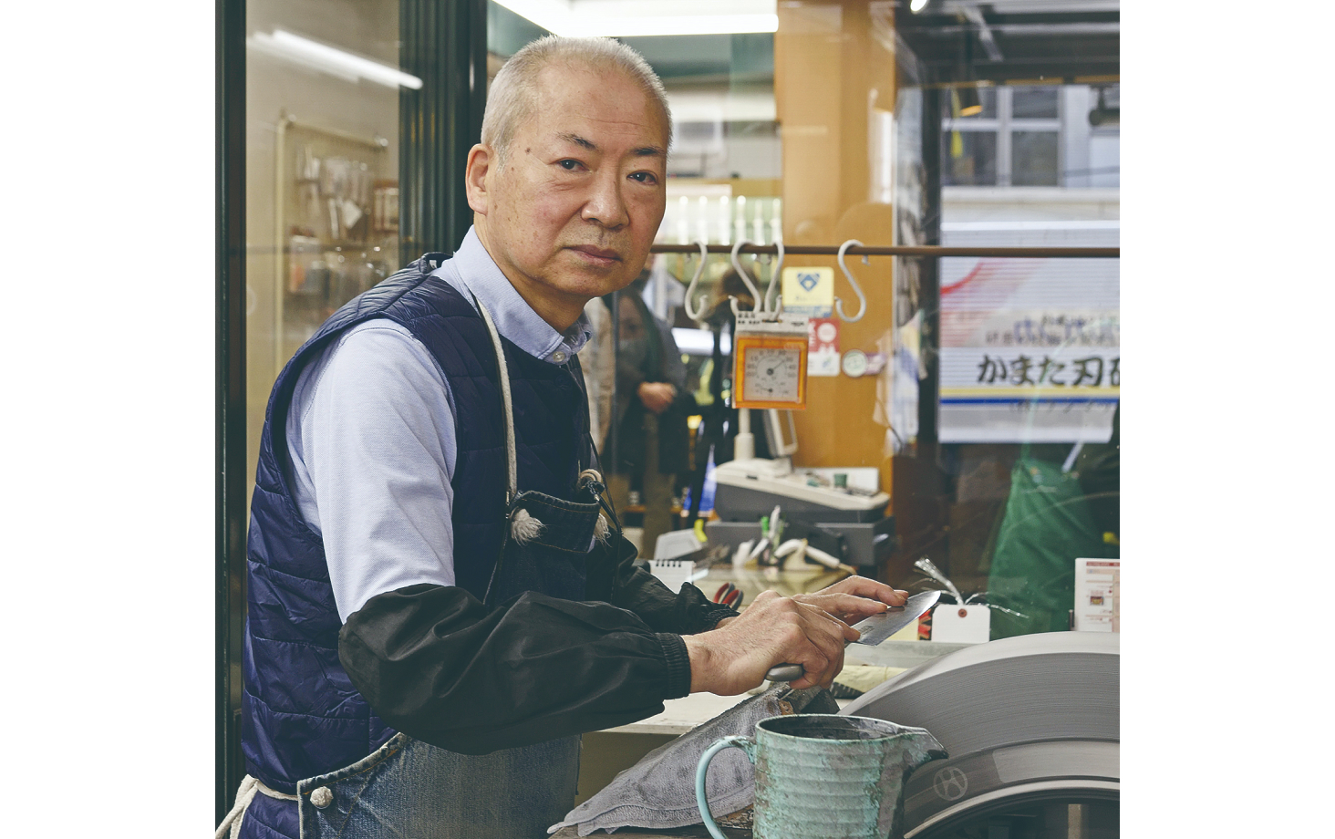 Kamata Seiichi sharpening a knife in the shop's work area